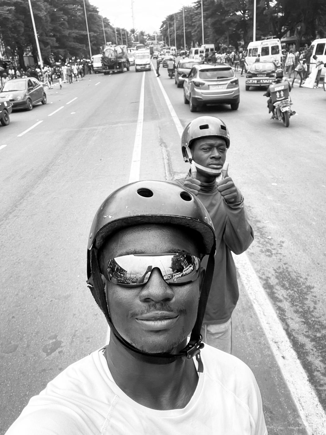 Selfie en noir et blanc, casque et lunettes, en roller au milieu de la circulation